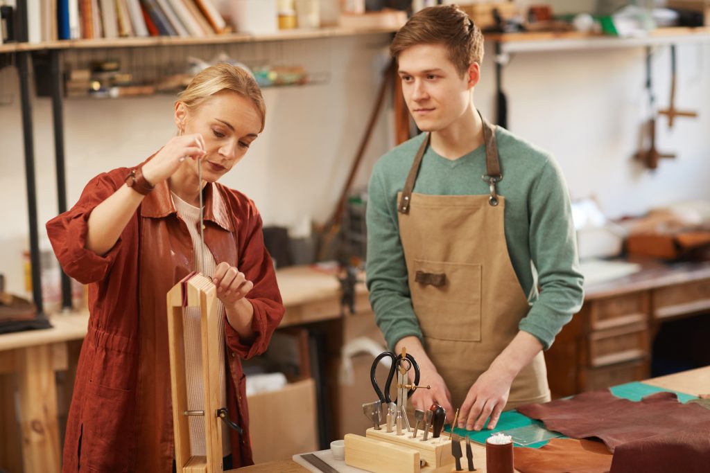 Two Artisans In Leathercraft Workshop